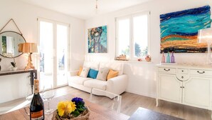 A bright living room with a white sofa, a coffee table, and a painting above the sofa.
