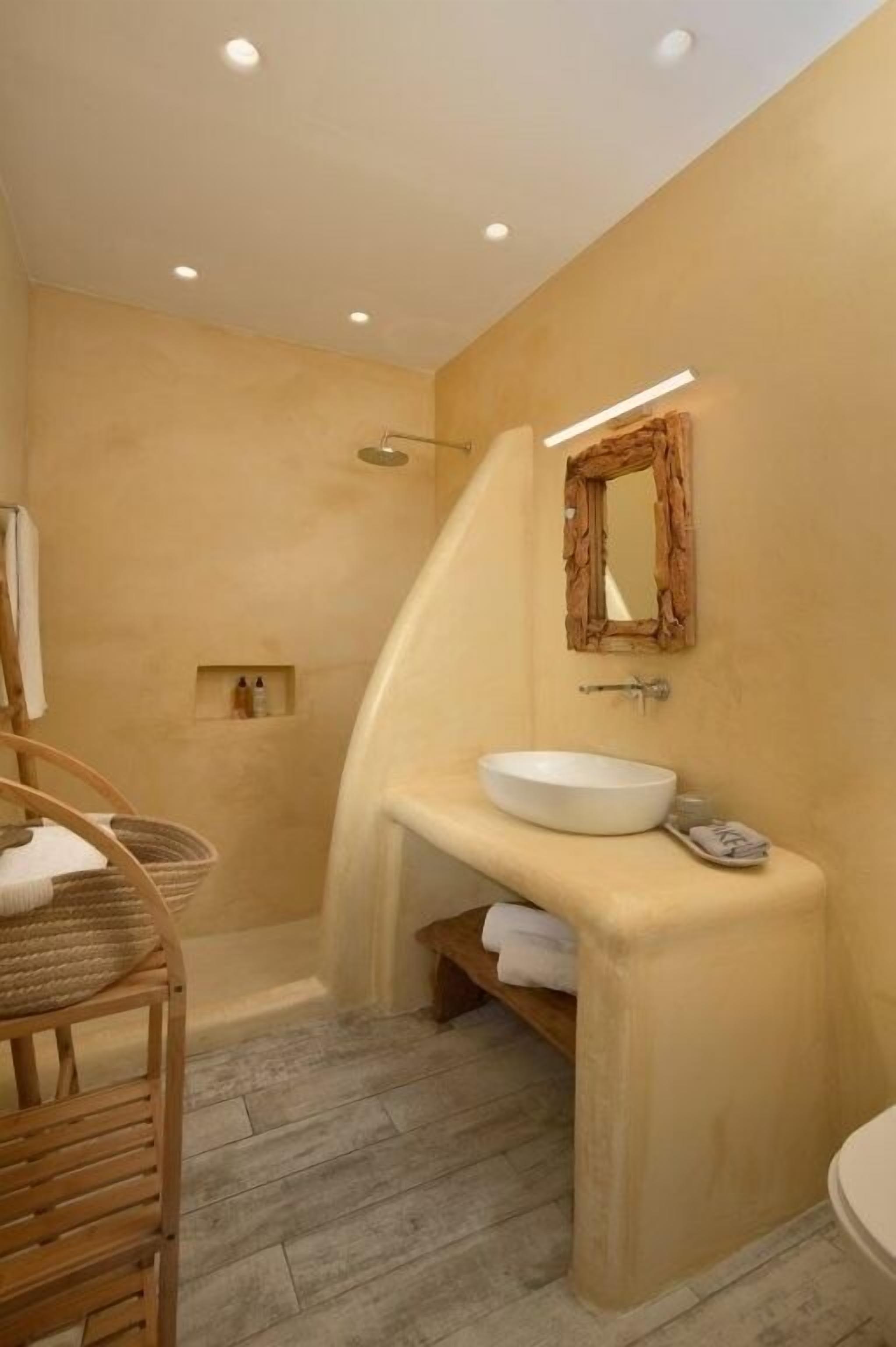 A bathroom with a curved vanity, a shower, and a wooden chair.