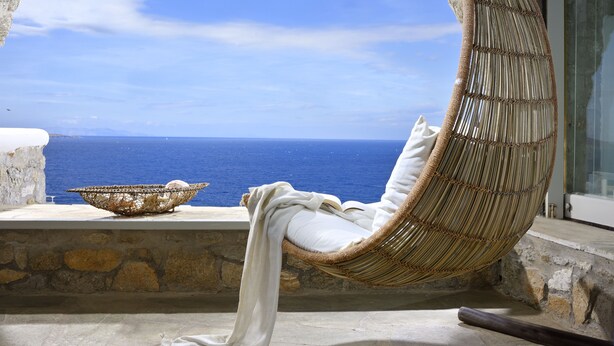 A wicker chair with a white cushion overlooking a stone balustrade with a view of the sea. - MYKONOS CALYPSO SUNSET LUXURY VILLA POOL-HOT TUB (MYKONOS)