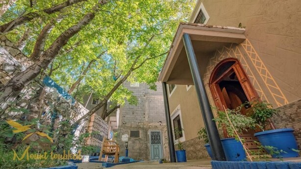 A courtyard with a stone wall, a wooden bench, and potted plants. - Mount Toubkal Lodge (Asni)
