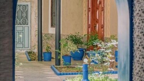 An arched entrance to a courtyard with potted plants and a pathway. - Mount Toubkal Lodge (Asni)