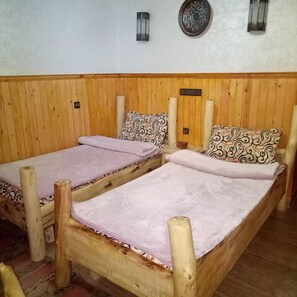 Una habitación de madera con dos camas, cada una con almohadas estampadas y una manta de color claro.
