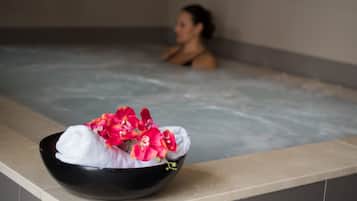Een wellness omgeving met een zwarte kom met een witte handdoek en roze bloemen op een aanrecht.