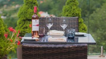 Ein Esstisch mit Wein, Gläsern und Besteck auf einem Balkon mit Bergblick.