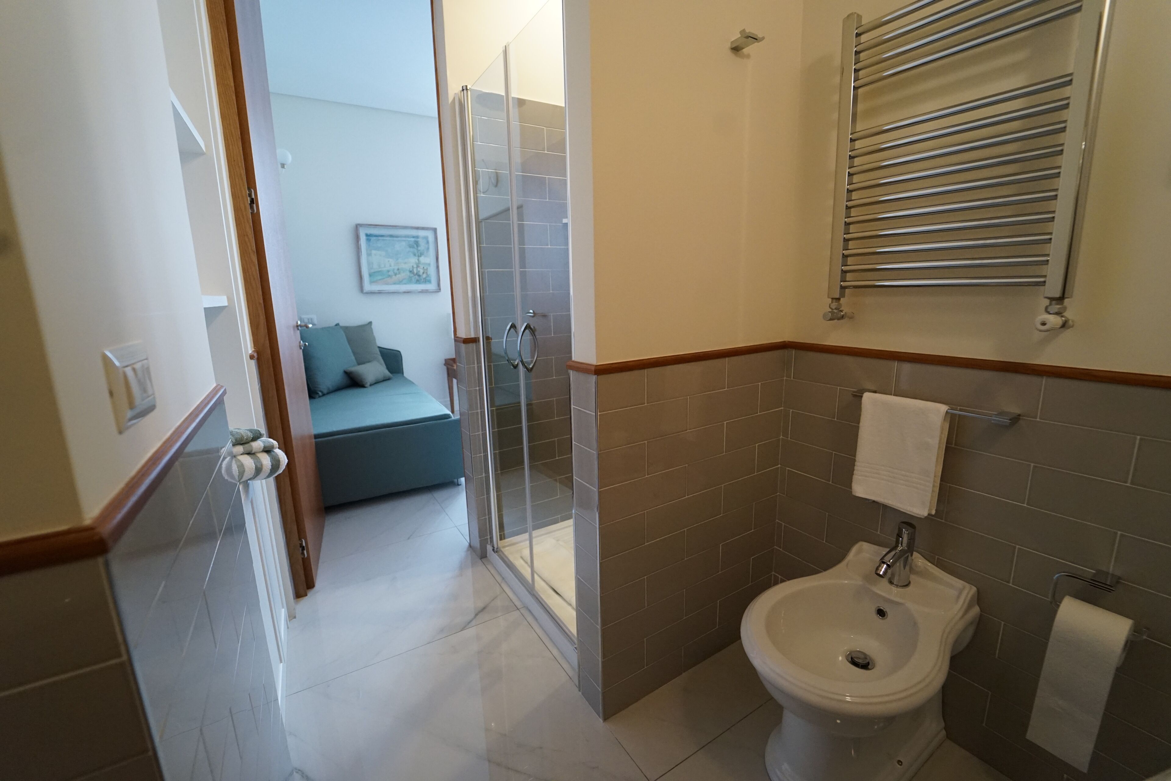 Une salle de bain équipée d’un bidet, d’un porte-serviettes et d’une douche à parois en verre.