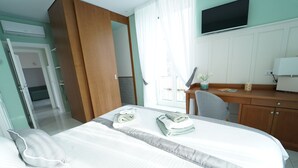 Hotelkamer met een bed, bureau, stoel, televisie en raam met gordijnen.