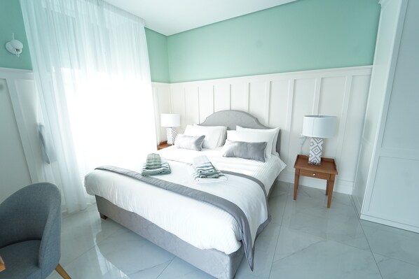 Une chambre bien rangée, avec un lit, des tables de chevet et une chaise.