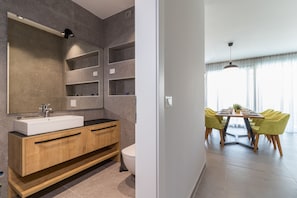 A modern bathroom with a large mirror, wooden vanity, and a toilet.