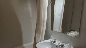 Un baño con un lavamanos blanco, un espejo y una bañera.