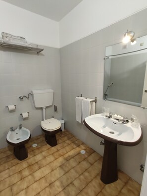 A bathroom with two toilets, a bidet, a sink, and a mirror. - Mafra Guest House (Mafra)
