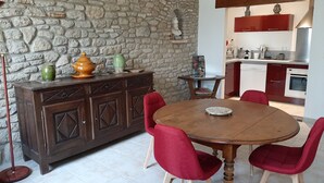 Un coin repas avec un mur en pierre, un buffet en bois et des chaises rouges.