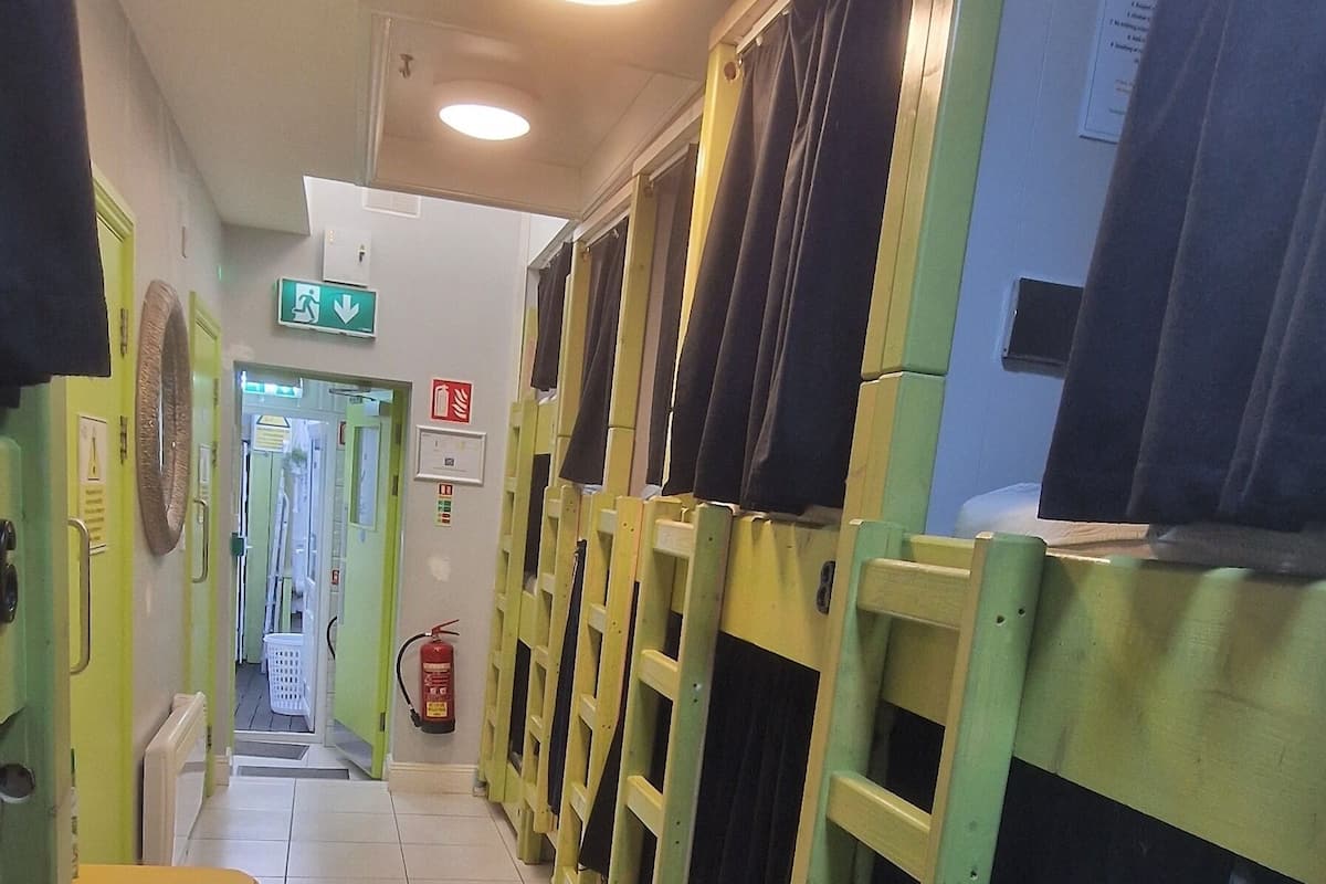 A hotel corridor with bunk beds, a trash bin, and a fire extinguisher.