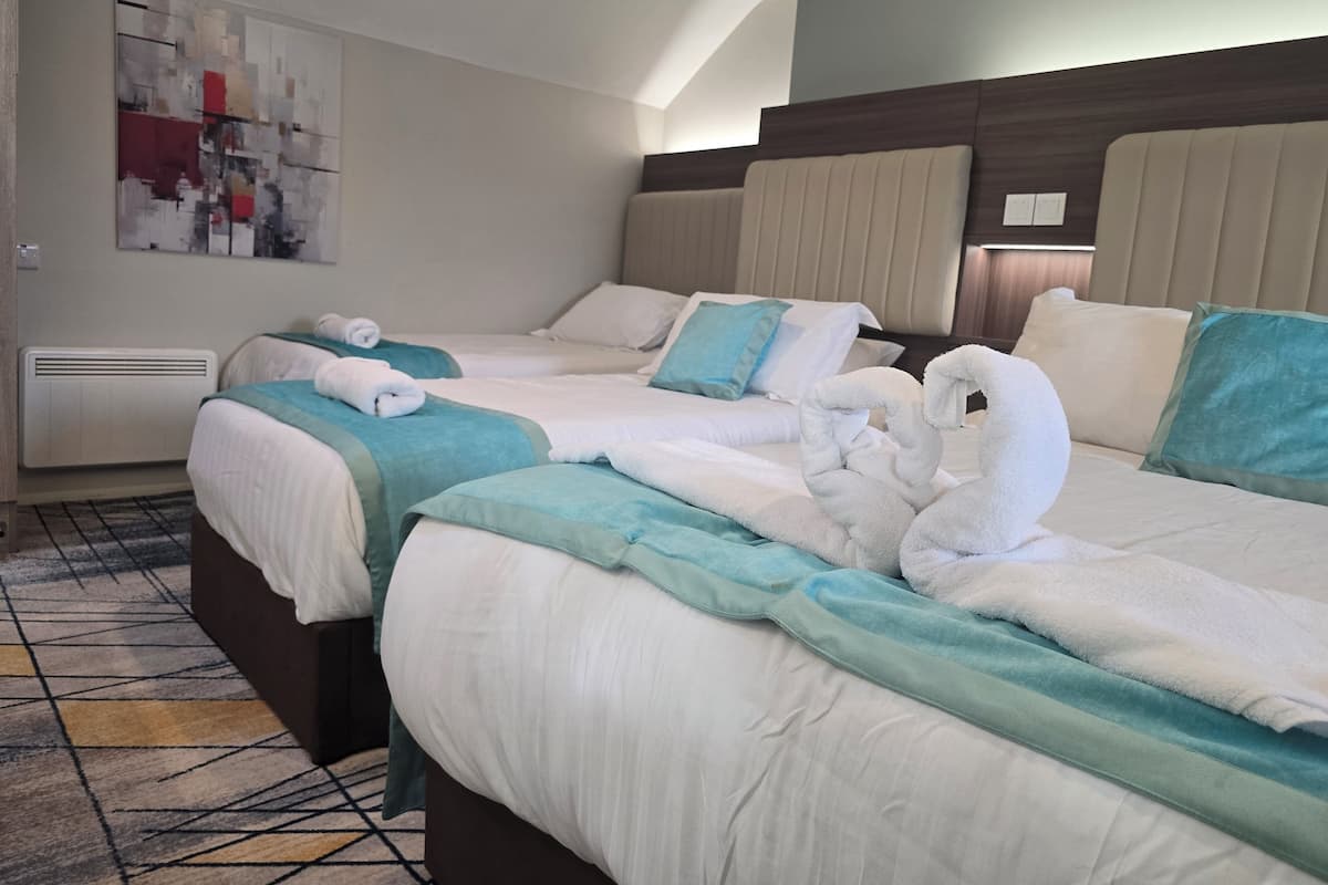 A hotel room with two beds, each with a headboard, a large abstract painting on the wall, and a patterned carpet.