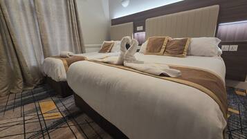 A hotel room with two beds, a large headboard, and a patterned carpet.