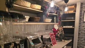 A kitchen area with a coffee machine, shelves with baskets, and a festive decoration.