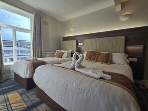 Habitación de hotel con dos camas, un ventanal grande y vistas a edificios.