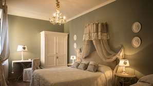 Un dormitorio con una cama grande, un armario, una mesita de noche con lámpara y un candelabro.