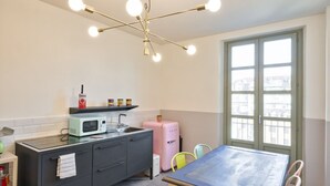 Een compacte keuken met een moderne kroonluchter, een raam met uitzicht en een eethoek met een tafel en stoelen.
