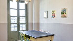 Een kamer met een tafel, stoelen, een deur en decoratie aan de muur.