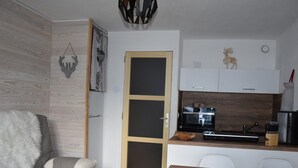 Une cuisine moderne équipée d’un four à micro-ondes, d’un grille-pain et d’un bloc à couteaux. On y trouve une table à manger en bois et un canapé gris agrémenté d’un coussin moelleux.