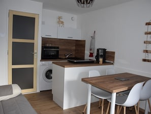 A compact kitchen with a washing machine, microwave, and coffee maker.