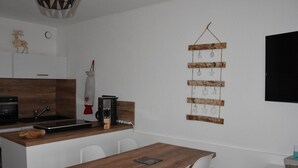 Une cuisine moderne avec un plan de travail en bois, des chaises blanches et une décoration suspendue.