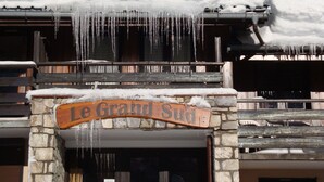 Une enseigne en bois portant l’inscription « Le Grand Sud », au-dessus d’une entrée en pierre ornée de stalactites qui pendent du toit.
