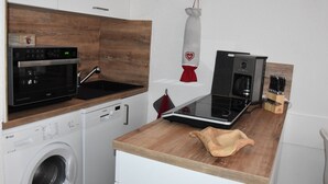 Une cuisine compacte équipée d’un four à micro-ondes, d’un four traditionnel, d’une machine à café et d’un bloc à couteaux.