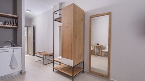Quarto moderno e minimalista, com armário embutido de madeira, um pequeno banco e um espelho grande.