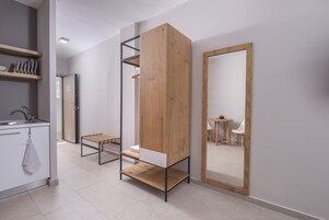 A modern, minimalist room with a built-in wooden wardrobe, a small bench, and a large mirror.