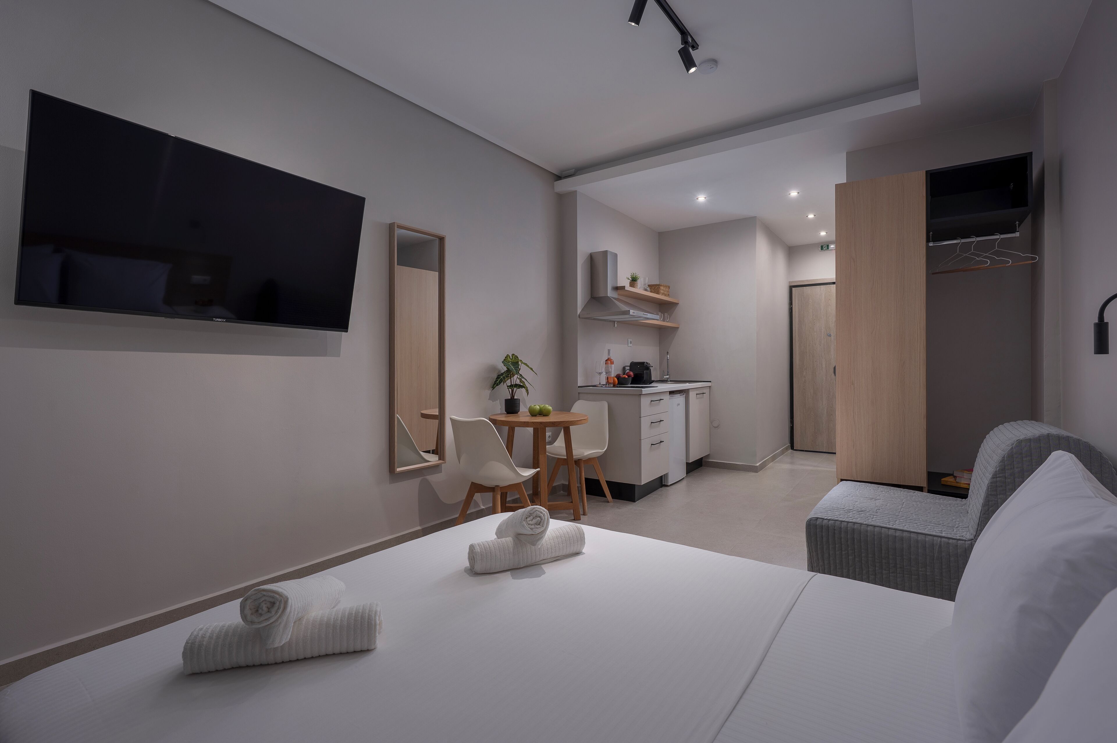 Une chambre d’hôtel moderne équipée d’un lit, d’une télévision, d’un bureau et d’une kitchenette.