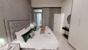 A modern hotel room with a large bed, a bedside table, a tray with breakfast, and a wardrobe.
