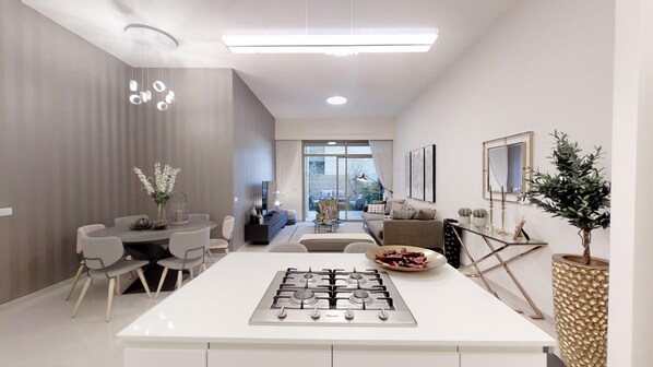 A modern kitchen with a central island, dining area with chairs, and a view to the outside.