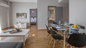 A modern dining area with a glass table, black chairs, and a bowl of fruit. - Cozy Apartment in Syntagma - Plaka by GHH (Athens)
