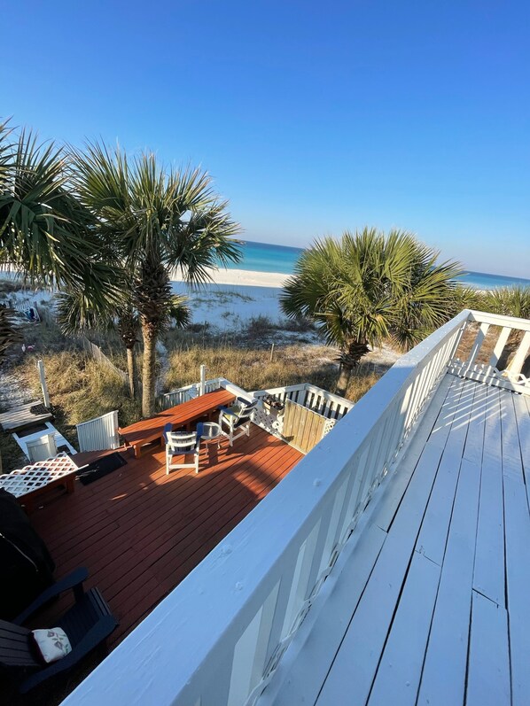Eine Holzterrasse mit Blick auf Strand und Meer.