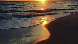 Una puesta de sol sobre el océano con olas en la playa.