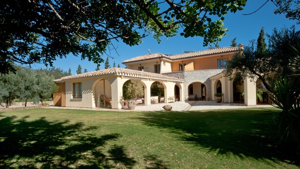A two-story house with a patio area, arched walkways, and a lawn. - S'Arenada Hotel (Villasimius)