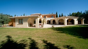A Mediterranean-style villa with a spacious patio, outdoor seating, and a well-maintained lawn. - S'Arenada Hotel (Villasimius)