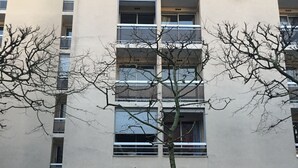 Un edifici de diverses plantes amb una entrada central, grans finestres i una moto aparcada.