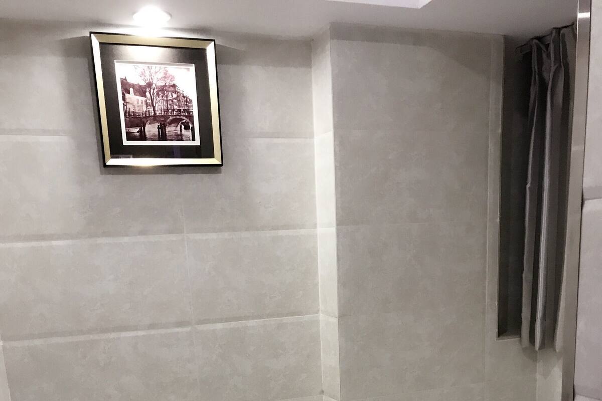 A hotel room with a bed, a framed picture on the wall, and a window with curtains.