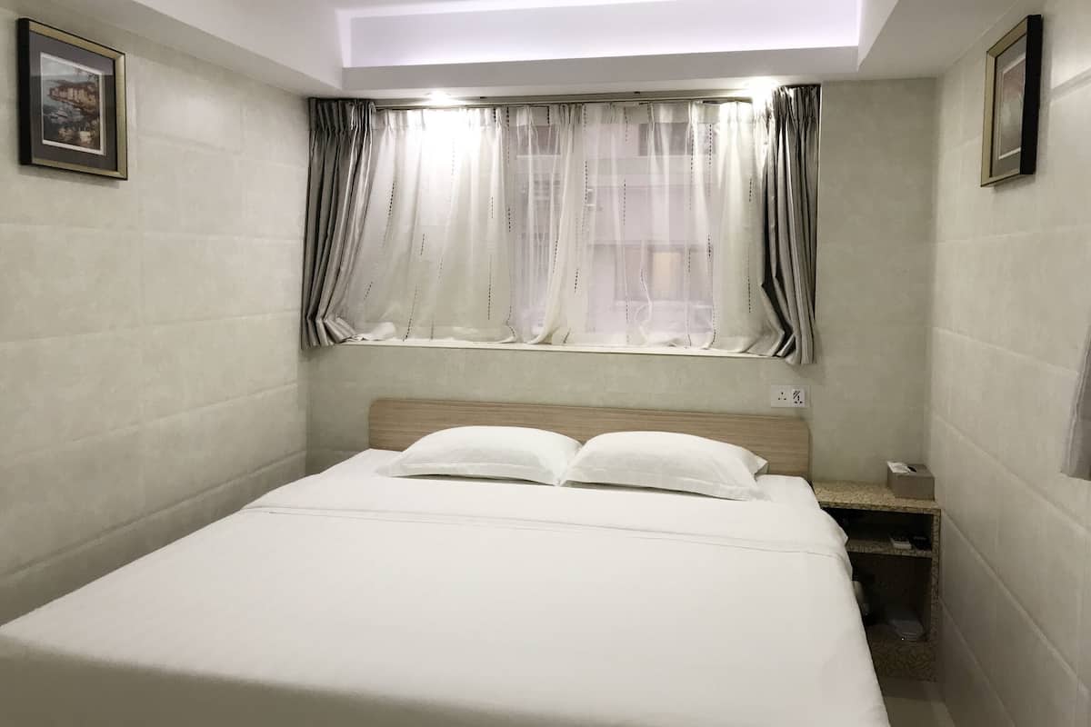 A bedroom with a bed, a nightstand, a window with curtains, and a ceiling light.