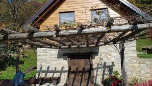 A rustic wooden house with a stone foundation, a wooden fence, and a garden with flowers. - Relaxing Cottage Donacka Gora (Rogatec)