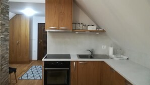 A kitchen with wooden cabinets, a countertop, a sink, and a stove. - Relaxing Cottage Donacka Gora (Rogatec)