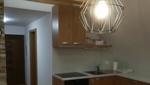 A kitchen with wooden cabinets, a black oven, and a white countertop. - Relaxing Cottage Donacka Gora (Rogatec)