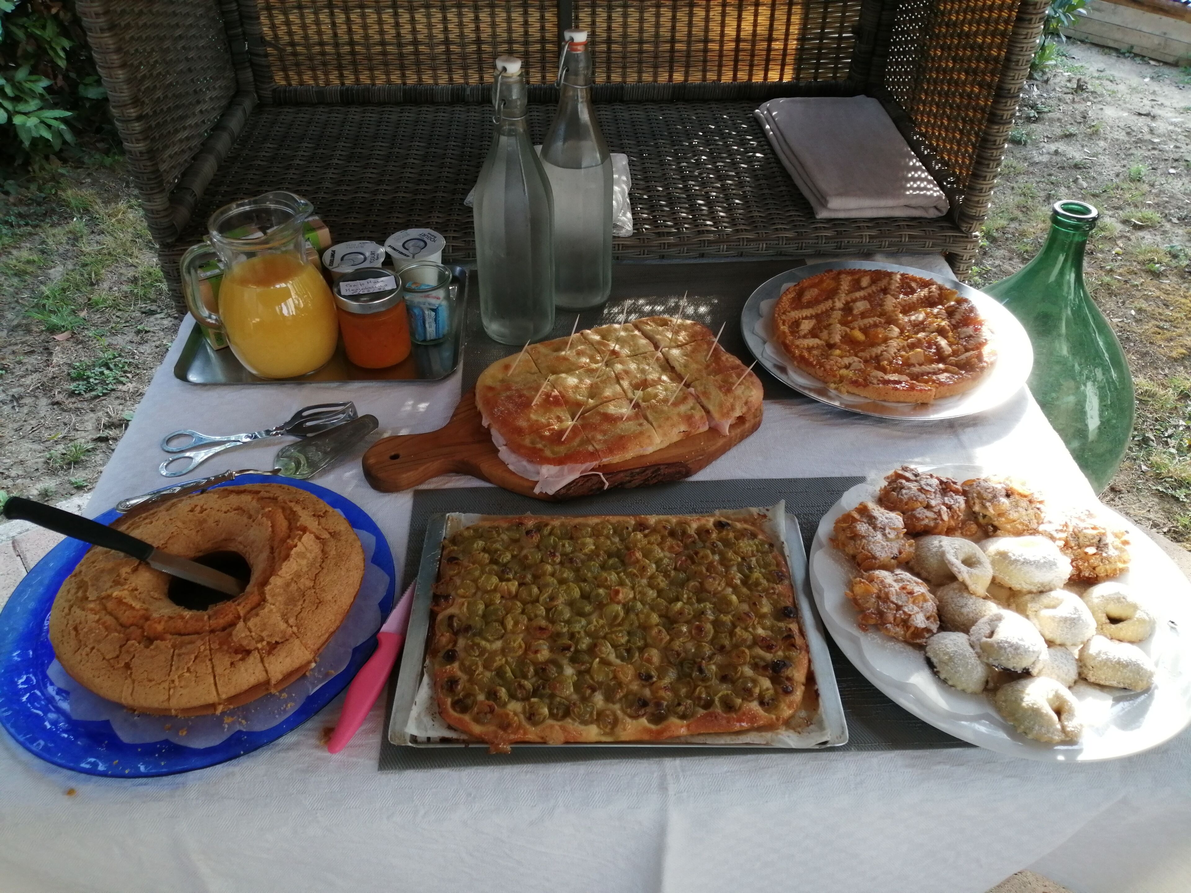 Ein Picknick mit verschiedenen Speisen, Besteck und Soßen auf einem Tisch im Freien.