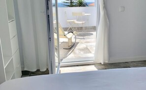 Une pièce dotée d’une porte-fenêtre coulissante donnant sur une terrasse extérieure avec une table et des chaises.