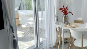 Et moderne spiseområde med et hvidt bord, stole og en vase med røde blomster.