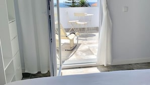 En balkon med et bord og stole, havudsigt og et lyst interiør.