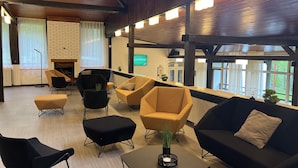 A modern lounge area with multiple seating options, a fireplace, and large windows offering a view of the outdoors.