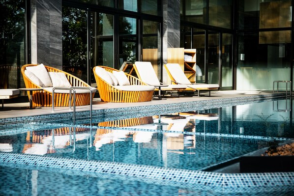A modern indoor pool area with wicker lounge chairs and a clear pool. - Garden Terrace Fukuoka Hotel & Resort (Fukuoka)
